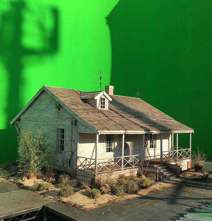 A scale model of a ranch house on a green screen background