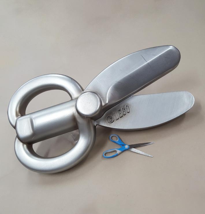 A pair of up-scaled Lego toy scissors, with a normal pair of scissors next to it for scale